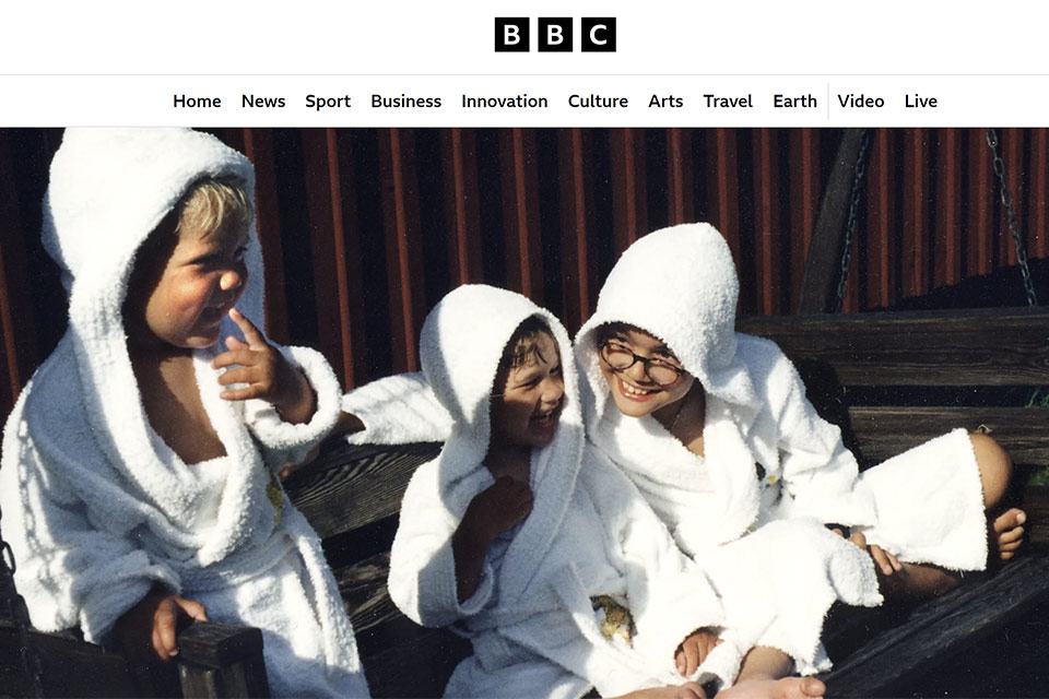 Skärmbild från BBC:s webbplats med en bild på Wille, Hugo och Emma i vita badrockar på en hammock.