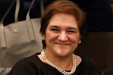 Domenica Taruscio, direktör vid ISS i Rom, ler varmt där hon sitter bland publiken, klädd i pärlhalsband.