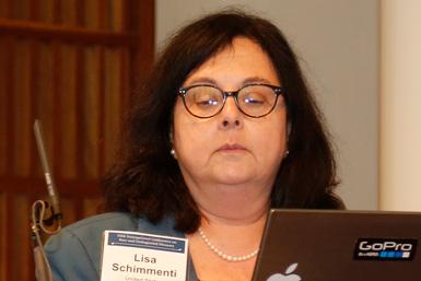 Professor Lisa Schimmenti från Mayo Clinic, med konferensnamnskylt och pärlhalsband, tittar ner mot en bärbar dator.