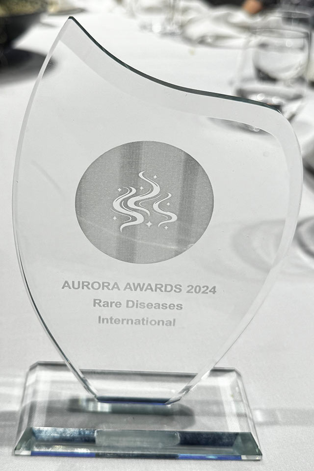 Glass Aurora Awards 2024 trophy engraved with Rare Diseases International, standing on a white tablecloth at the gala dinner.