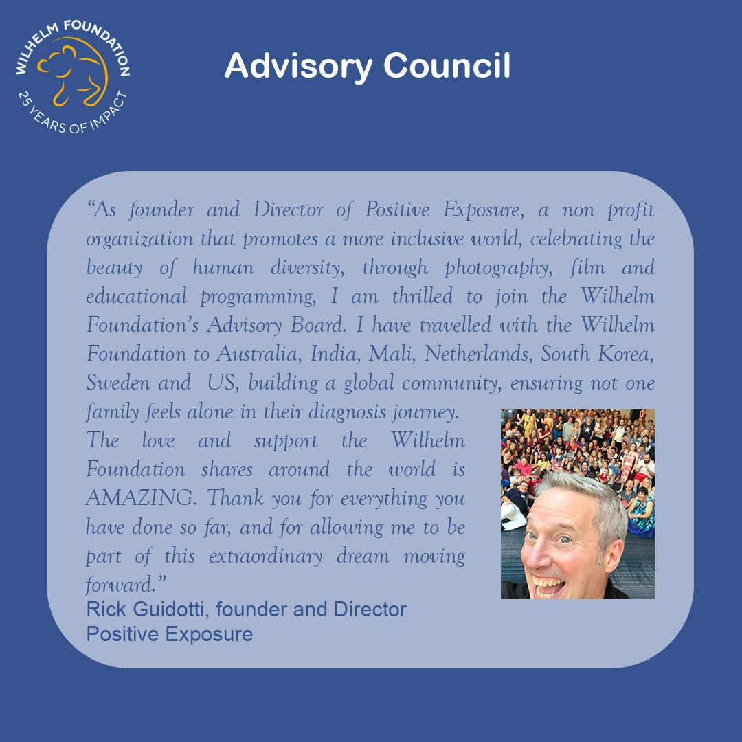 Graphic with a blue background titled “Advisory Council,” featuring the Wilhelm Foundation “25 Years of Impact” logo in the top left. A rounded light-blue text box contains a quote about inclusion, human diversity, and global community-building through Wilhelm Foundation, describing travels to multiple countries and the importance of ensuring no family feels alone on their diagnostic journey. The quote is attributed to Rick Guidotti, Founder and Director of Positive Exposure. On the right side is a lively portrait of Rick Guidotti smiling in the foreground, with a large, diverse group of people gathered behind him.