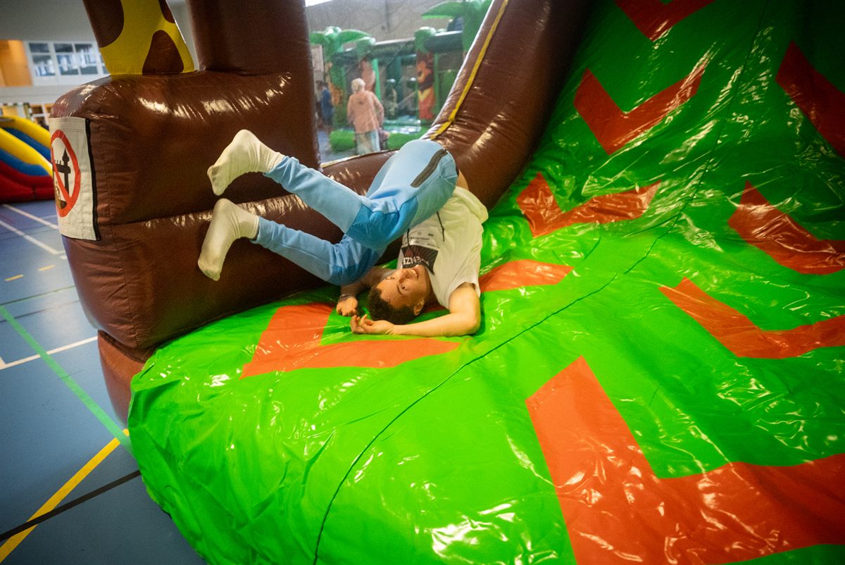 A young man laughing on an inflatable obstacle course at the Family Camp