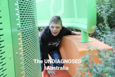En glad pojke klättrar genom en grön och orange lekställning utomhus, med texten The UNDIAGNOSED Australia.
