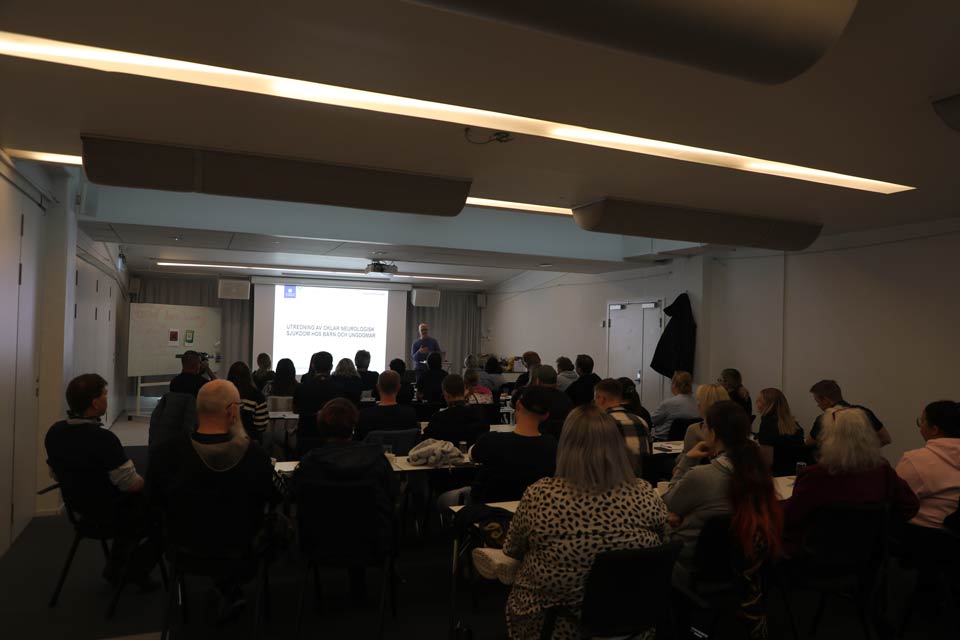 A photo from the back of a lecture room. With a lot of people looking forward to the speaker