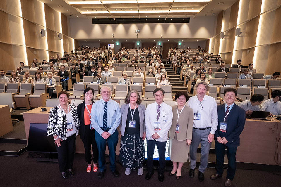 Eight people are standing in front of nearly 300 people seated in an auditorium.