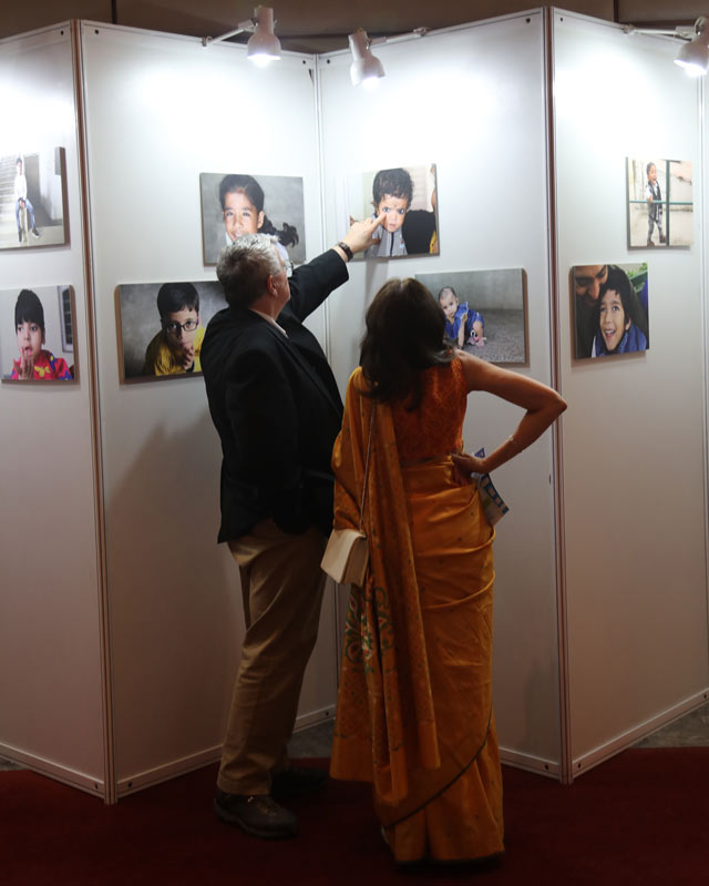 A man and a woman in Sari at a photo exhibition. The man points to a child's eyes.