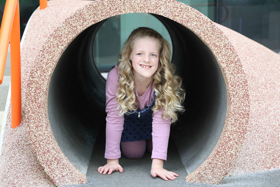 Girl crawling through a large cement pipe in a playground

