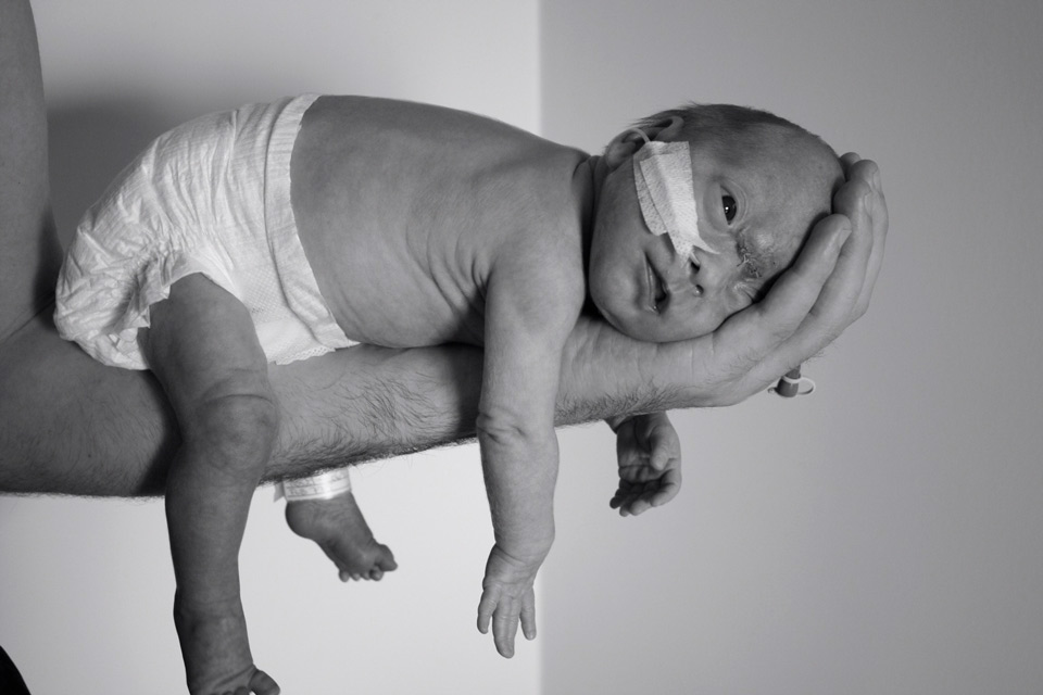 Liten baby som ligger på pappans arm med huvudet i pappans handflata
