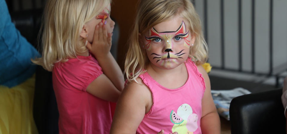 Little girl with a face painting of a cat.