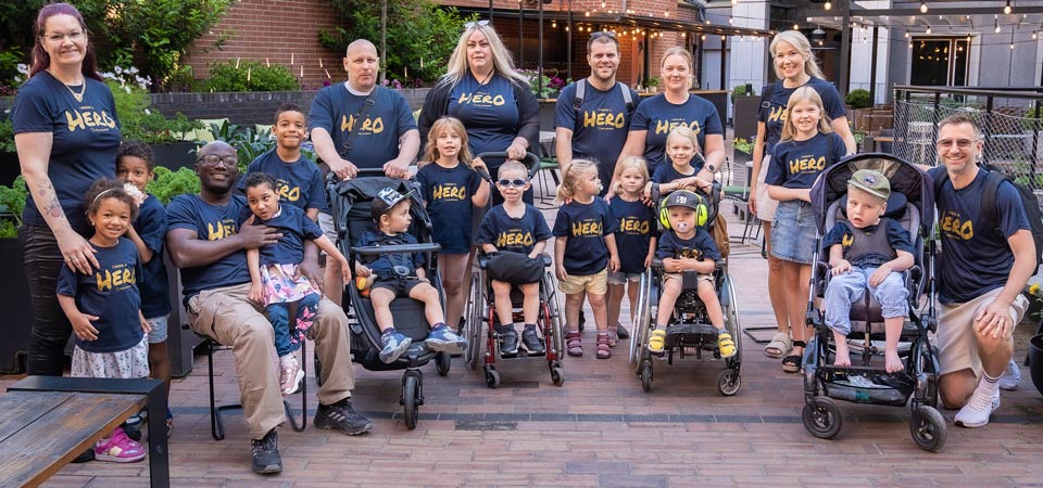 Families with some of children in wheel chairs. All have blue T-shirt with "I know a Hero"