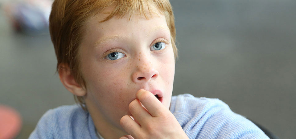 A girl with blue eyes and red short hair. She is wearing a blue jumper